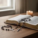 Rosary and prayer book beside a softly glowing candle