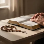 Rosary, Bible, and prayerful hands in a softly lit home corner