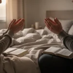 Person praying quietly beside a bed during a difficult morning